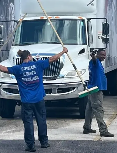 Two men are holding a mop and smiling.