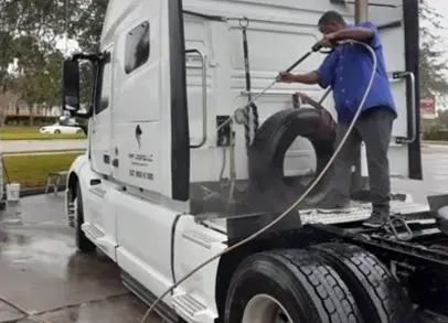 A man is washing the tires on his truck.