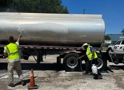 Two men in safety vests are working on a truck.